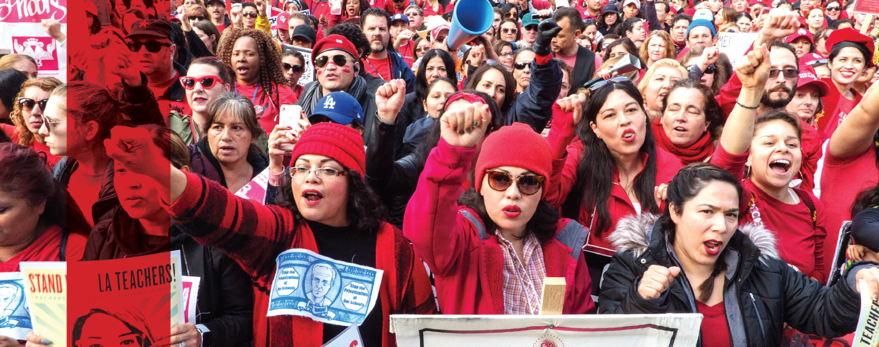 A sea of educators wearing red chants together and hold their firsts in the air, holding signs saying Stand with LA Teachers